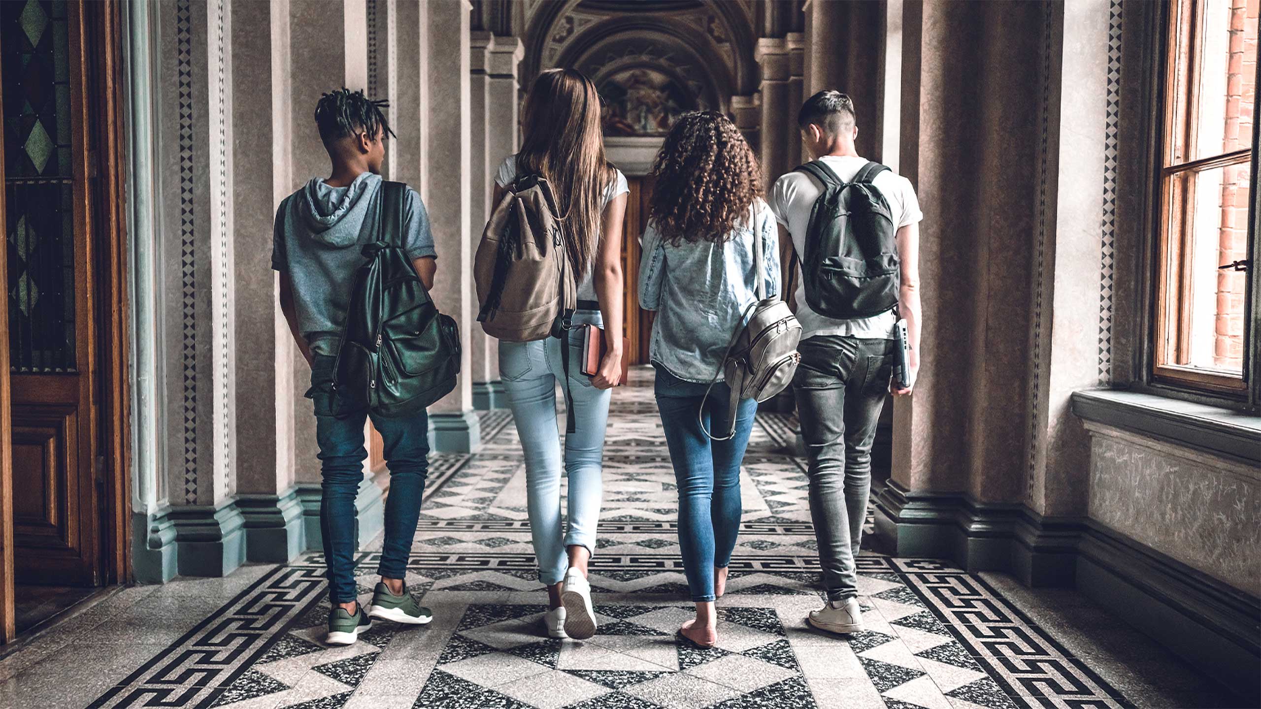 A diverse group of students walking down a university corridor